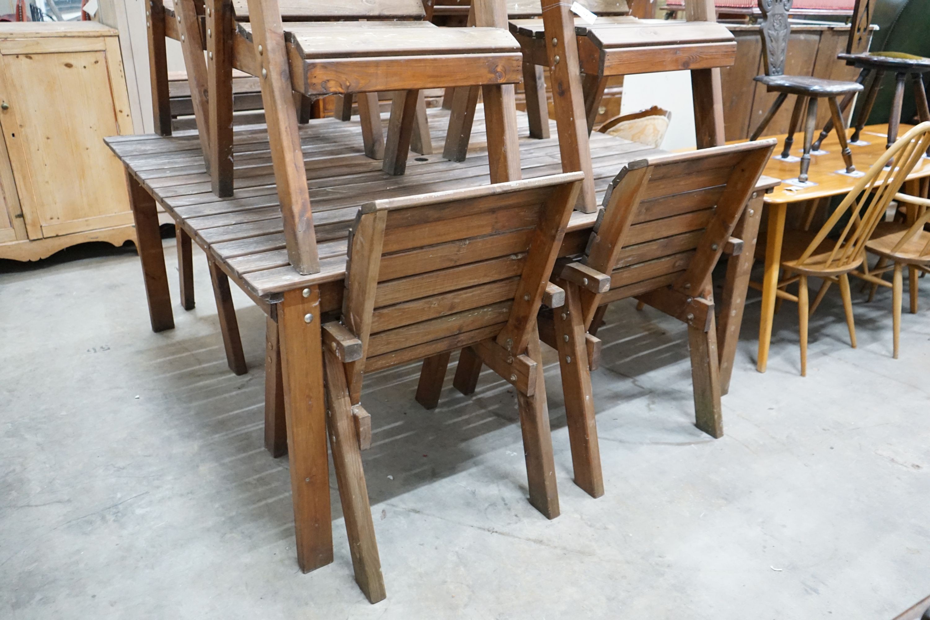 A large rectangular slatted wood garden table, length 174cm, depth 162cm, height 79cm together with eight matching elbow chairs